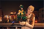 Tune in for charming Christmas time in Venice, Italy. Portrait of happy young woman with Christmas tree standing on a bridge