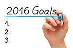 Hand writing 2016 Goals with blue marker on transparent wipe board isolated on white.