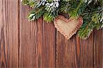 Christmas tree branch with snow and heart toy on wooden table. Top view with copy space