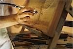 Adult man at work as artist, chiselling a bas-relief in his atelier. He works with a drill to ceasel a wood painting.