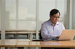 Singapore, Senior businessman using laptop at desk