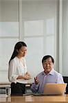 Singapore, Two business people talking at desk in office
