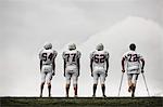 A group of football players, young people in sports uniform and protective helmets. One person using crutches.