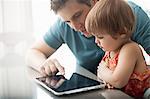 A father and his daughter looking at a digital tablet, using the touch screen.