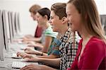 A group of young people, boys and girls, students in a computer class working at screens.