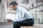 A man sitting using a digital tablet.