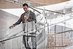 A man standing on spiral stairs checking his smart phone.