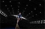 A young woman gymnast performing on the beam, balancing on a narrow piece of apparatus.