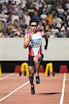 Japanese male sprinter running on track