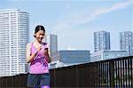 Young Japanese woman with smartphone before her run downtown Tokyo