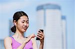 Young Japanese woman with smartphone before her run downtown Tokyo