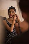 Singapore, Woman putting on earring in front of mirror