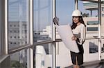 Singapore, Female architect with hardhat looking at building plans