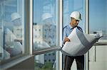 Singapore, Male architect with hardhat looking at building plans