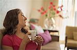 Woman on sofa with coffee cup smiling