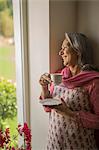 Mature woman at window with tea cup