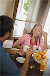 Woman in pink smiling at man at dining table