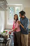 Man with hands on shoulders of woman while she cooks, smiling
