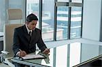 Businessman using mobile phone and taking notes at desk