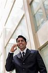 India, Businessman standing outside office building, talking on mobile phone