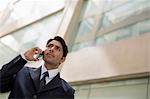 India, Businessman in suit talking on mobile phone outside office building