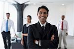 India, Smiling business man standing with arms crossed in front of colleagues