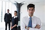 India, Business man standing with arms crossed in front of colleagues