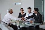 India, Senior businessman shakes hand of younger man in meeting