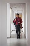 India, Man walking down corridor with jacket over shoulder and phone in hand