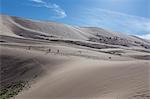 Distant people descending a huge sand dune, iridescent on a summer evening, Khongoryn Els, Gobi Desert, Mongolia, Central Asia, Asia