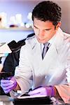 Life scientist researching in laboratory. Attractive young male scientist looking at the microscope slides in laboratory. Healthcare and biotechnology concept.