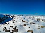 Aerial view of narrow road in snowy landscape of mountain pass Aurlandsfjellet in Norway on sunny day