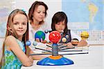 Kids study the solar system under their teacher supervision - focus on the little girl in front
