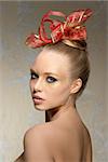 charming woman with stunning visage and freckles posing with naked shoulders in beauty close-up shoot with christmas glitter golden make-up and red ribbon in the hairdo