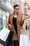 pretty young woman , in coat going for shop in winter time, she is carrying some shopping bag
