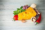 Part cheese with vegetables and basil on wooden board