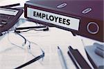 Ring Binder with inscription Employees on Background of Working Table with Office Supplies, Glasses, Reports. Toned Illustration. Business Concept on Blurred Background.