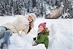 Winter outdoors can be fairytale-maker for children or even adults. Happy mother pointing in camera to child while playing outdoors