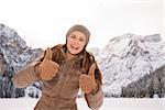 Energy-filling and exciting winter weekends in the mountains. Portrait of happy young woman showing thumbs up outdoors among snow-capped mountains