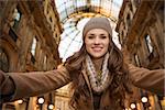 Get ready to making your way through shopping addicted crowd. Huge winter sales in Milan just started. Happy young woman shopper taking selfie in Galleria Vittorio Emanuele II
