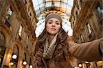 Get ready to making your way through shopping addicted crowd. Huge winter sales in Milan just started. Glamour young woman shopper taking selfie in Galleria Vittorio Emanuele II