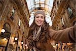 Get ready to making your way through shopping addicted crowd. Huge winter sales in Milan just started. Smiling young woman shopper taking selfie in Galleria Vittorio Emanuele II