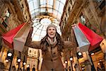 Get ready to making your way through shopping addicted crowd. Huge winter sales in Milan just started. Happy young woman with shopping bags in Galleria Vittorio Emanuele II rejoicing real bargain