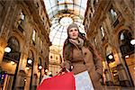 Get ready to making your way through shopping addicted crowd. Huge winter sales in Milan just started. Vogue young woman with shopping bags in Galleria Vittorio Emanuele II looking into the distance