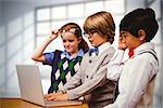 Pupils using laptop against room with large windows showing city