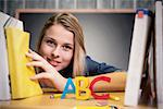 Pretty student in the library against blackboard with copy space on wooden board