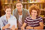 Fashion students using tablet  against close up of a bookshelf