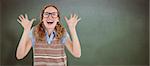 Geeky hipster woman smiling and showing her hands  against green chalkboard
