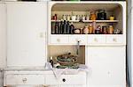 Jars and bottles of home-made food on retro style kitchen cabinet