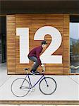 Urban cyclist balancing on bicycle in front of numbered wooden wall